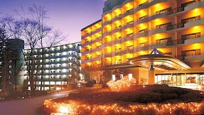 Un hôtel à plusieurs étages, doté d’un design moderne, avec un atrium central et une façade bien éclairée.