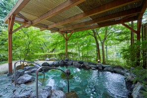 A hot spring area with a wooden pergola, surrounded by rocks and lush greenery. - Hotel Harvest Kinugawa (Nikko)
