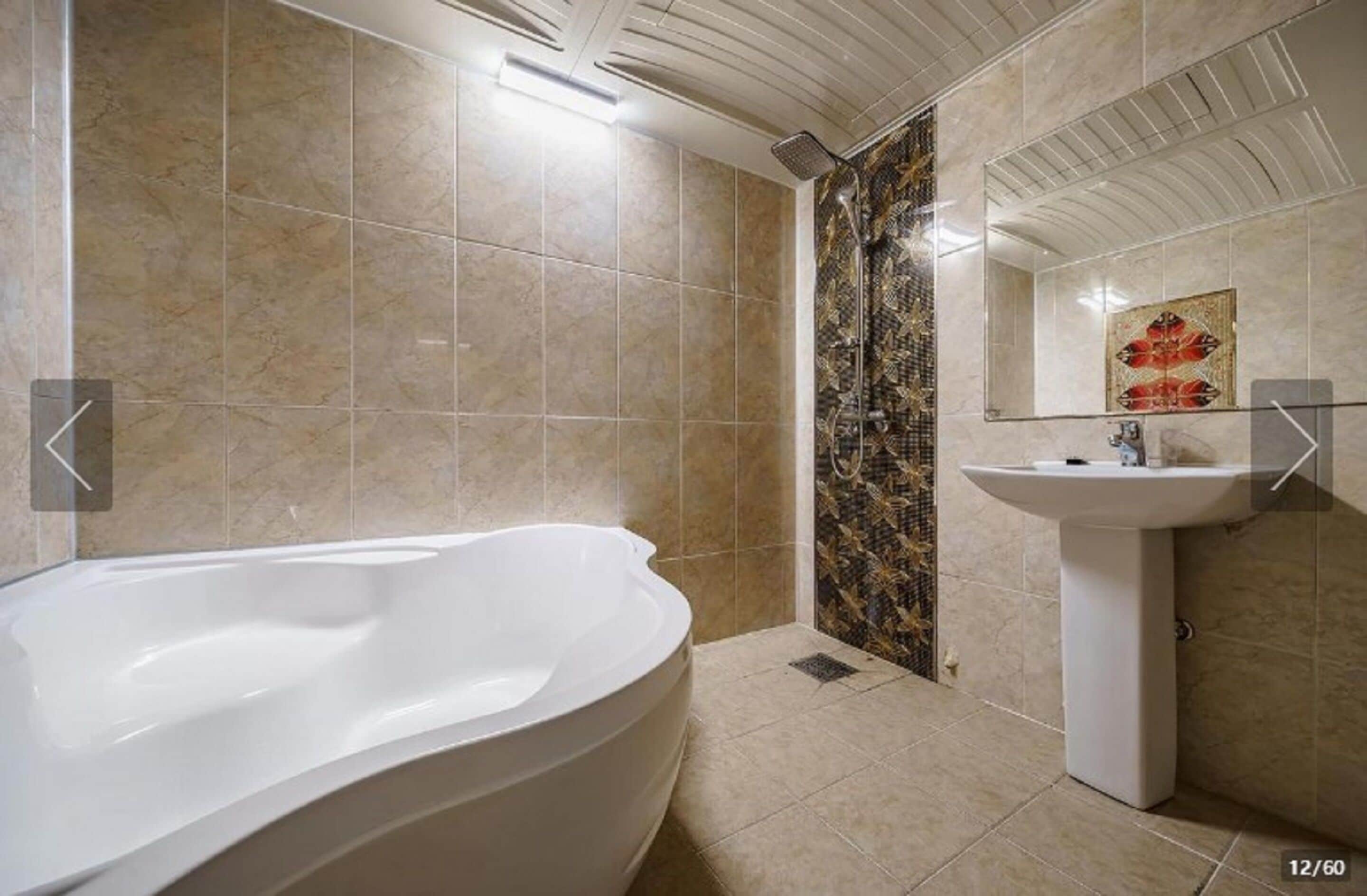 Un baño moderno con una bañera independiente, una ducha con un revestimiento decorativo y un lavamanos sobre pedestal.