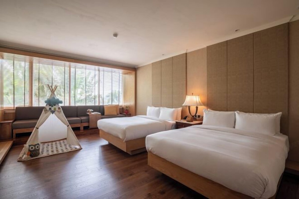Ein Hotelzimmer mit zwei Betten, einer Couch, einem Zelt und Blick ins Freie.