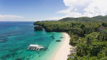 Di pantai, pasir putih, kursi berjemur, dan payung pantai