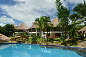 A resort with multiple buildings, a swimming pool, and lush greenery. - Amun Ini Beach Resort & Spa (Anda)