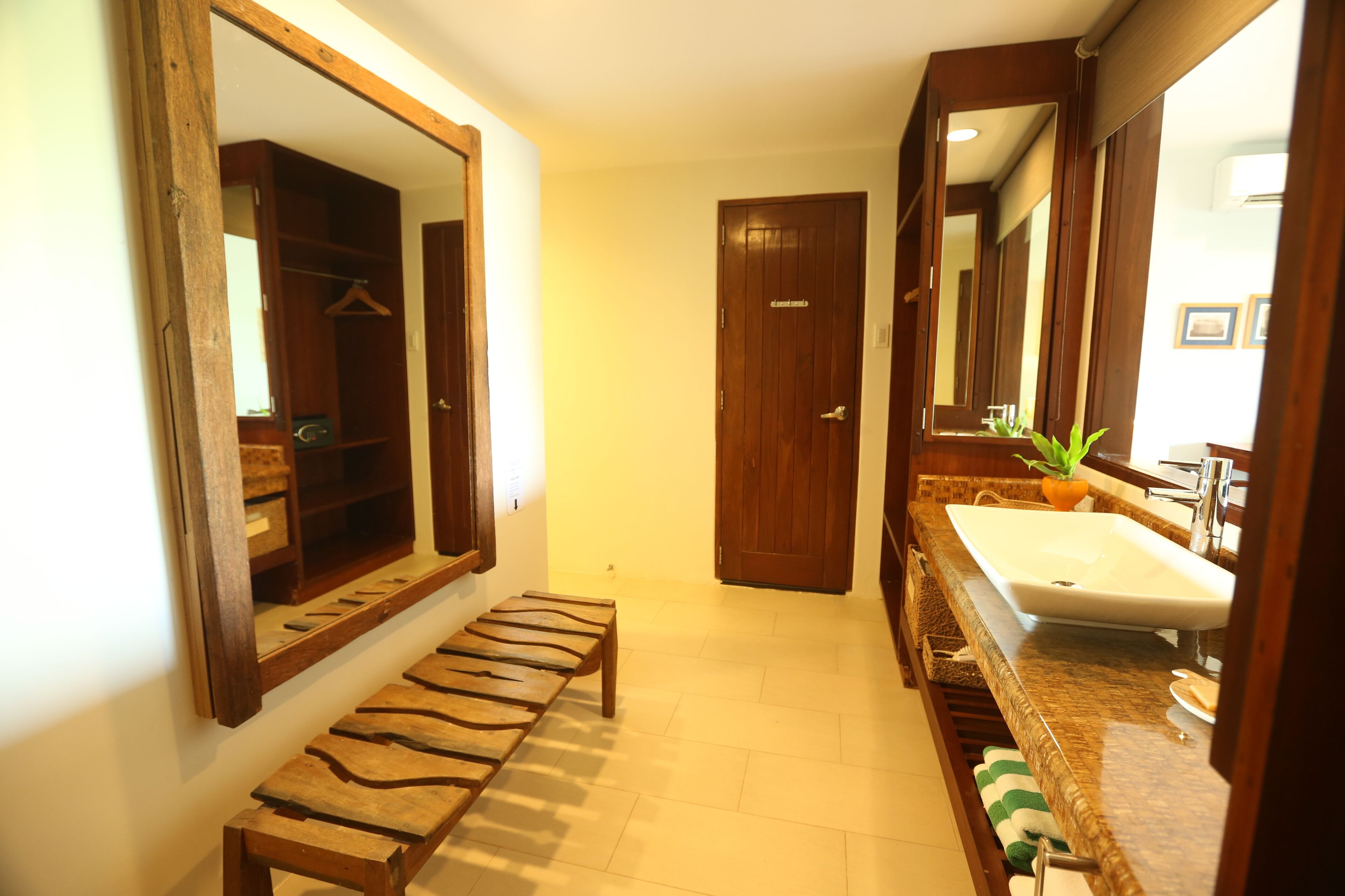 A bathroom with a wooden bench, a sink, and a mirror.