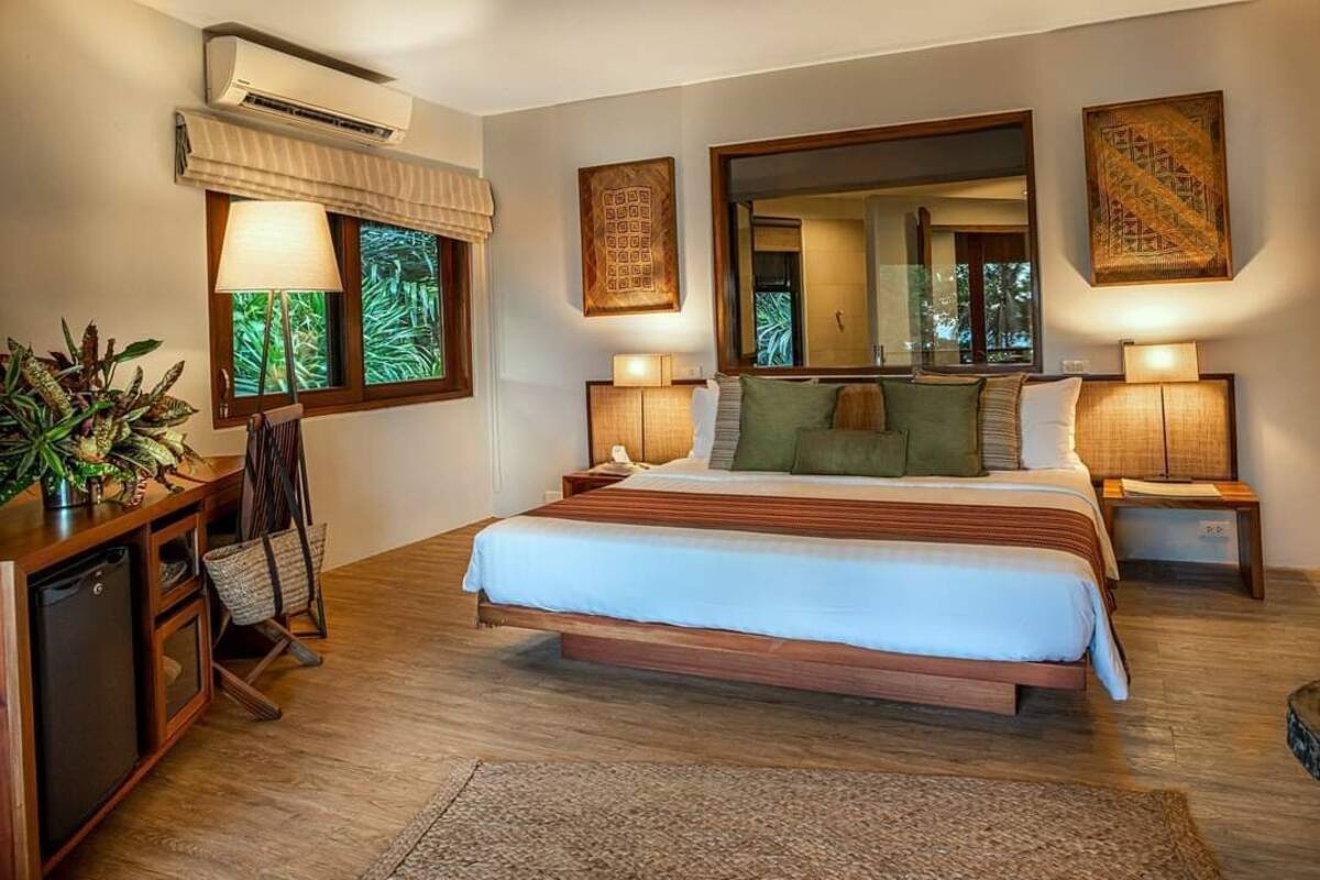 A bedroom with a large bed, bedside lamps, a small desk, and a mirror.