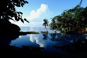 Una piscina al aire libre, una piscina con borde infinito, sombrillas