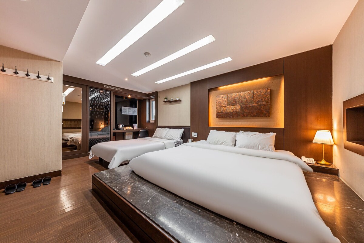 Une chambre d’hôtel avec deux lits, un grand miroir, un bureau et une vue sur la ville.