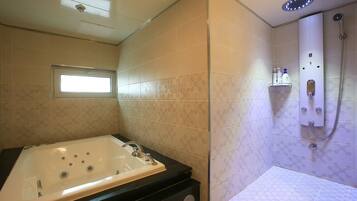 A bathroom with a bathtub, shower, and a window.