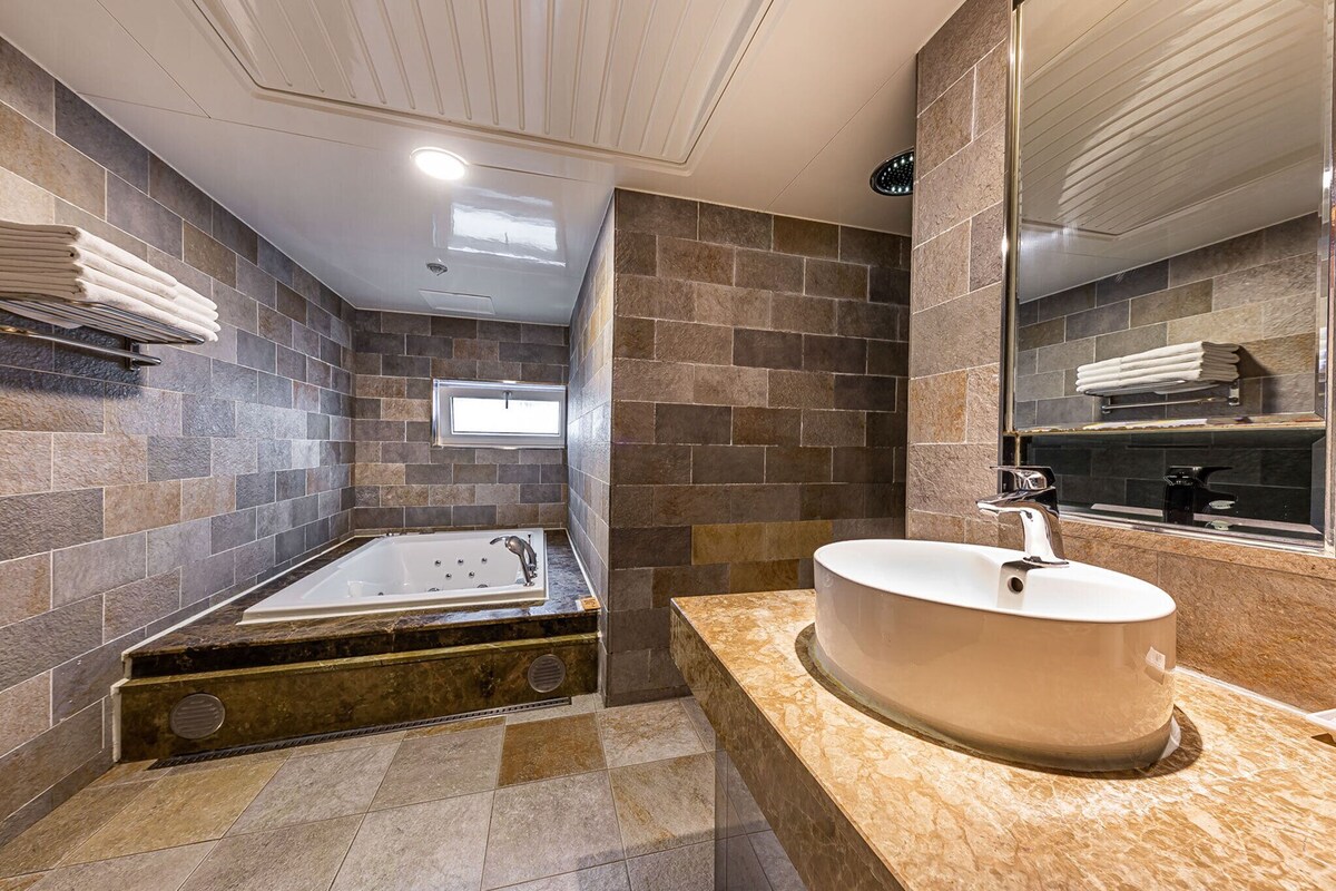 Une salle de bain moderne avec une grande baignoire, un lavabo rond et un miroir.