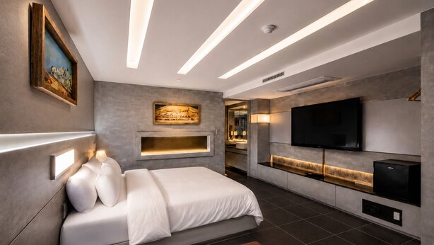 Une chambre moderne équipée d’un lit, de lampes de chevet, d’une télévision et d’un coin cuisine intégré.