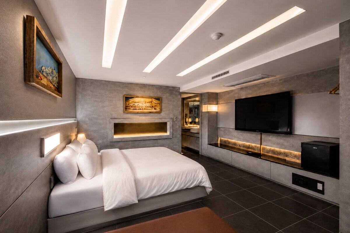 Une chambre moderne équipée d’un lit, de lampes de chevet, d’une télévision et d’un coin cuisine intégré.