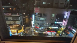 A nighttime cityscape with illuminated buildings and a busy street. - Friendly DH Naissance Hotel by Mindrum Group (Seoul)