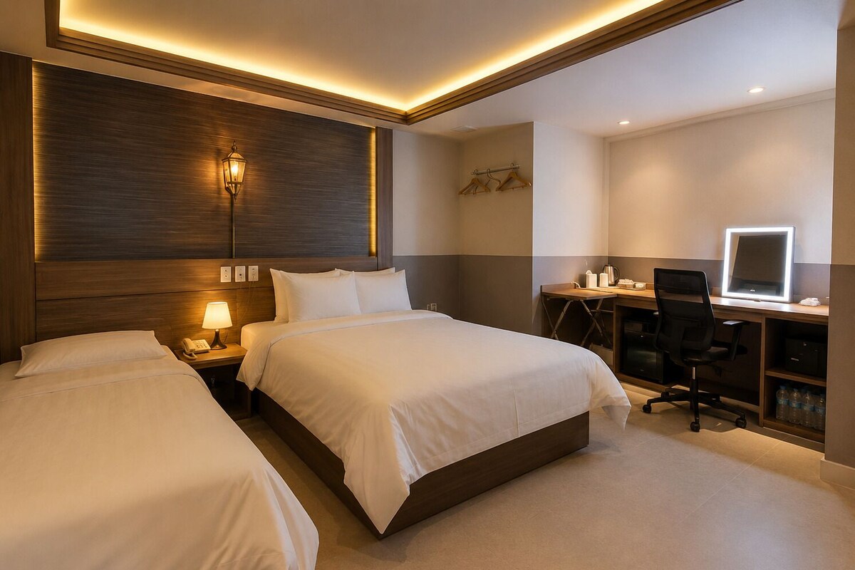Une chambre d’hôtel avec deux lits, un bureau avec un ordinateur, une chaise et un téléviseur fixé au mur.