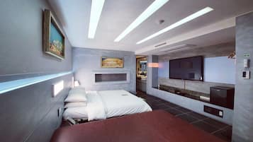 Une chambre d’hôtel moderne équipée d’un lit, de tables de chevet, d’un téléviseur à écran plat et d’un espace bureau intégré.