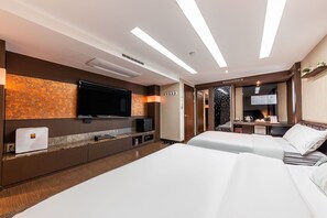 Habitación de hotel con dos camas, un televisor de pantalla plana, un minibar y un escritorio con cafetera.