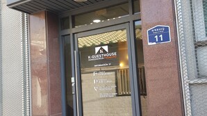 The entrance to K-GUESTHOUSE Dongdaemun Premium 2 with a glass door, a blue sign indicating room number 11, and a check-in/out schedule. - K-Guesthouse Dongdaemun Premium 2 (Seoul)