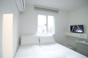 A hotel room with a bed, a television mounted on the wall, and a window with blinds. - K-Guesthouse Dongdaemun Premium 2 (Seoul)