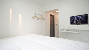 A hotel room with a bed, a television mounted on the wall, and a door leading to another room. - K-Guesthouse Dongdaemun Premium 2 (Seoul)