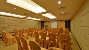 A conference room with rows of chairs, a projector screen, and a podium. - Lintas View Hotel (Kota Kinabalu)