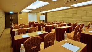 A conference room with multiple tables and chairs, equipped with water bottles and papers, and a projector screen. - Lintas View Hotel (Kota Kinabalu)