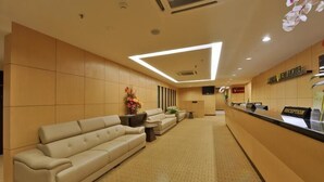 A hotel reception area with a reception desk, a sofa, and a wall-mounted TV. - Lintas View Hotel (Kota Kinabalu)