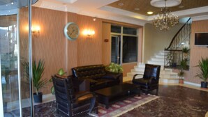 A spacious living area with a dark leather sofa set, a coffee table, and a chandelier. There is a staircase with a railing leading to an upper floor. - Nobel Hotel Ankara (Ankara)