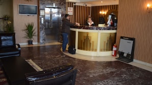 A hotel reception area with a marble floor, a reception desk, a television mounted on the wall, and a chandelier. - Nobel Hotel Ankara (Ankara)