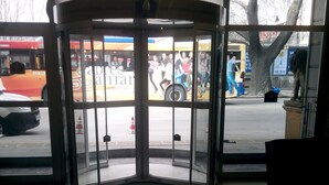 A revolving door with a glass panel, a tiled floor, and a view of a street with a bus and pedestrians. - Nobel Hotel Ankara (Ankara)