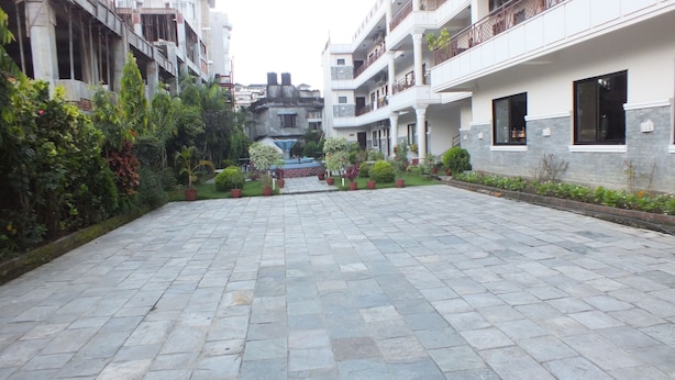 Un patio con pavimento de piedra, plantas en macetas y una fuente.