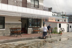 A building with a covered entrance, outdoor seating, and a bicycle parked outside. - Hotel Swapnabagh (Pokhara)