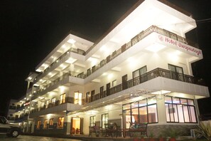 Un hôtel à plusieurs étages, doté de balcons, d'une entrée couverte et d'une enseigne indiquant son nom.