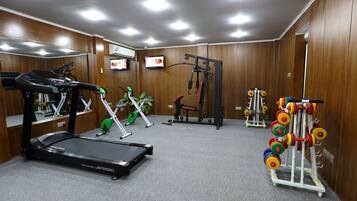 A gym with treadmills, weight machines, and a rack of colorful dumbbells.