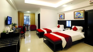 A hotel room with two beds, a desk, a TV, and a window with curtains. - Nascent Gardenia Baridhara (Dhaka)