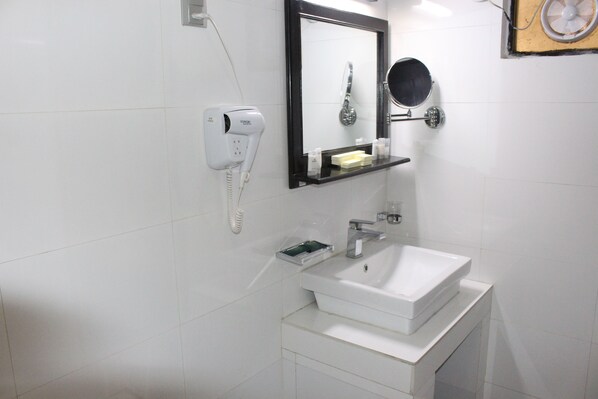 Un baño moderno con lavamanos blanco, un secador de pelo y un espejo.