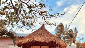 A beachside cafe with a thatched umbrella, wooden chairs, and a sign reading "AND BAAR cafe & bistro".