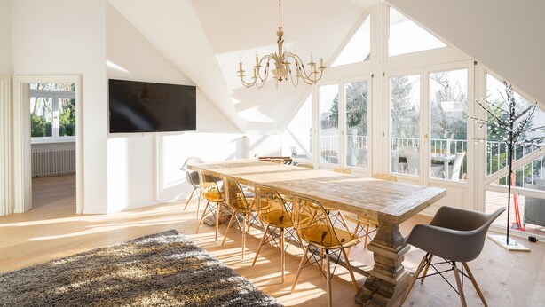 A spacious dining area with a long wooden table, clear glass chairs, and a chandelier. - GL Apartmenthouse (Wiesbaden)