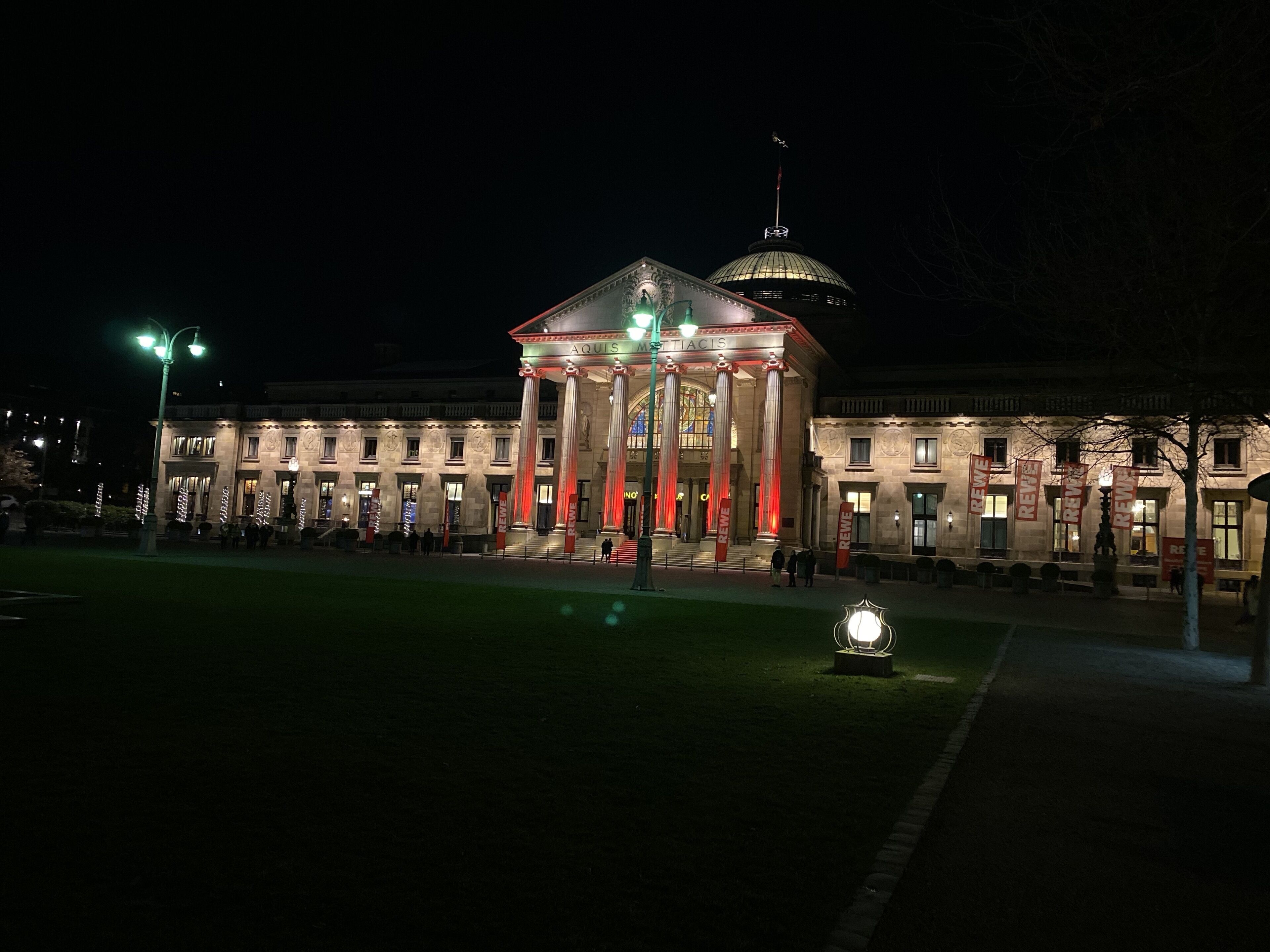A classical building with a central dome and columns, illuminated at night.