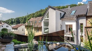 A modern house with a small pond, potted plants, and a balcony. - GL Apartmenthouse (Wiesbaden)
