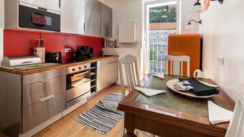 A modern kitchen with stainless steel appliances, a red backsplash, and a dining area with a wooden table and chairs.
