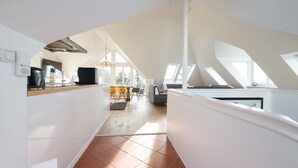 A modern kitchen with a high ceiling and skylights, a dining area with a view, and a spacious living area with a fireplace. - GL Apartmenthouse (Wiesbaden)