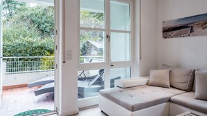 A modern living room with a large window, a white sofa, and a view of a balcony with outdoor furniture. - GL Apartmenthouse (Wiesbaden)