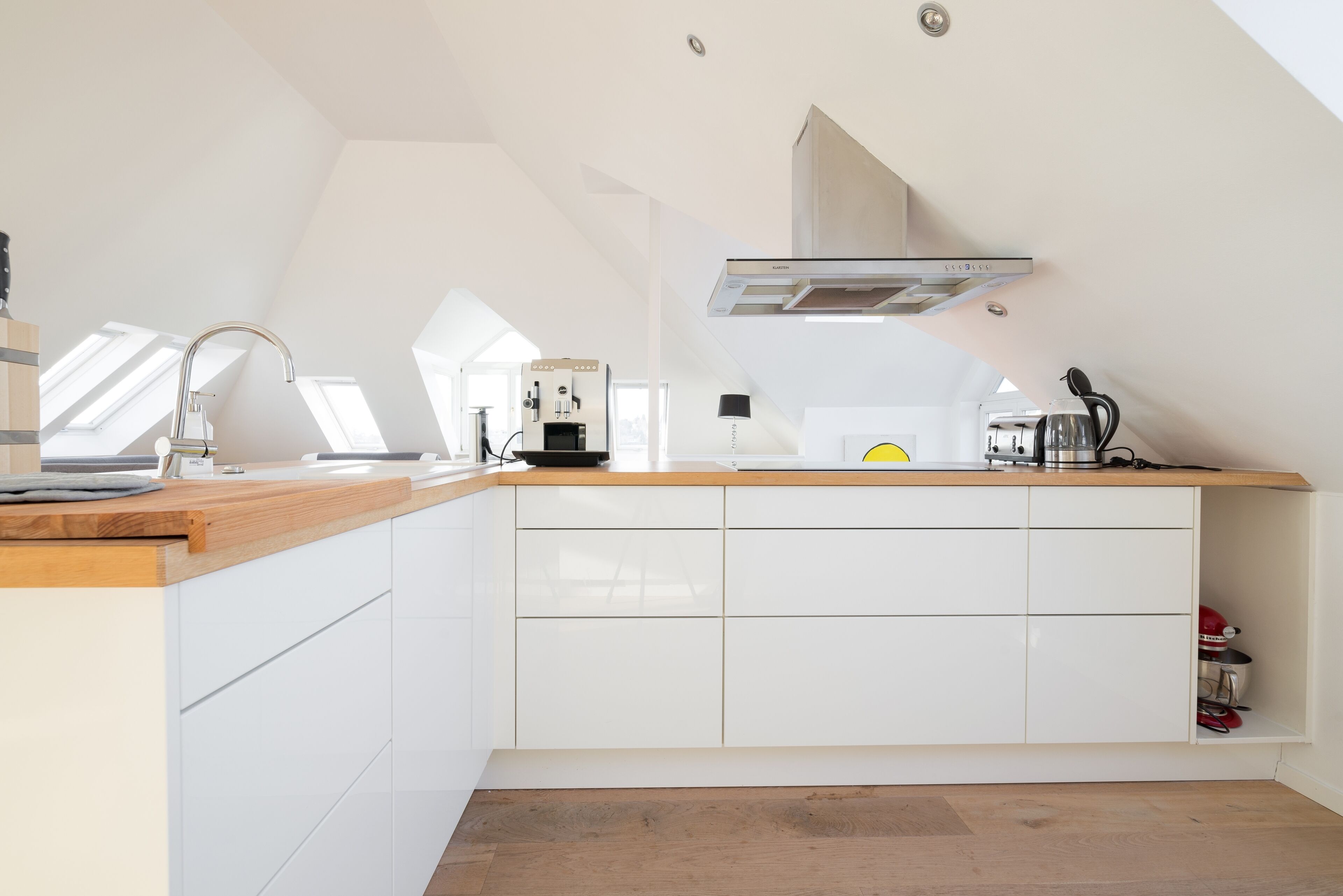 Een moderne keuken met witte kasten, een houten aanrecht en een ingebouwde kookplaat.
