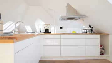 Een moderne keuken met witte kasten, een houten aanrecht en een ingebouwde kookplaat.