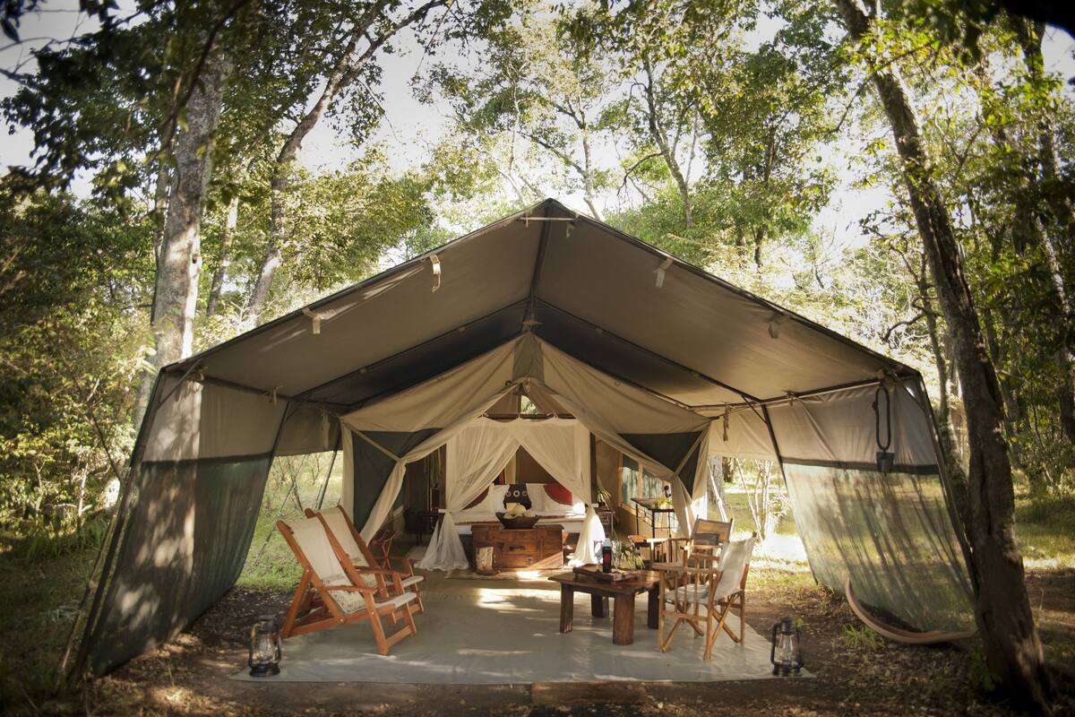 A tented accommodation with a dining area, chairs, and a table.