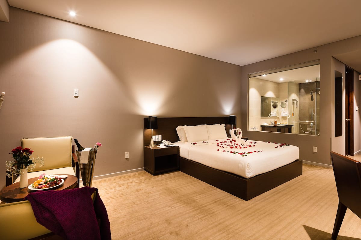 Ein modernes Hotelzimmer mit einem großen Bett, einem Nachttisch und einem Spiegel.