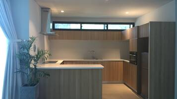 A modern kitchen with wooden cabinets, a central island, a built-in oven, and a window above the sink.