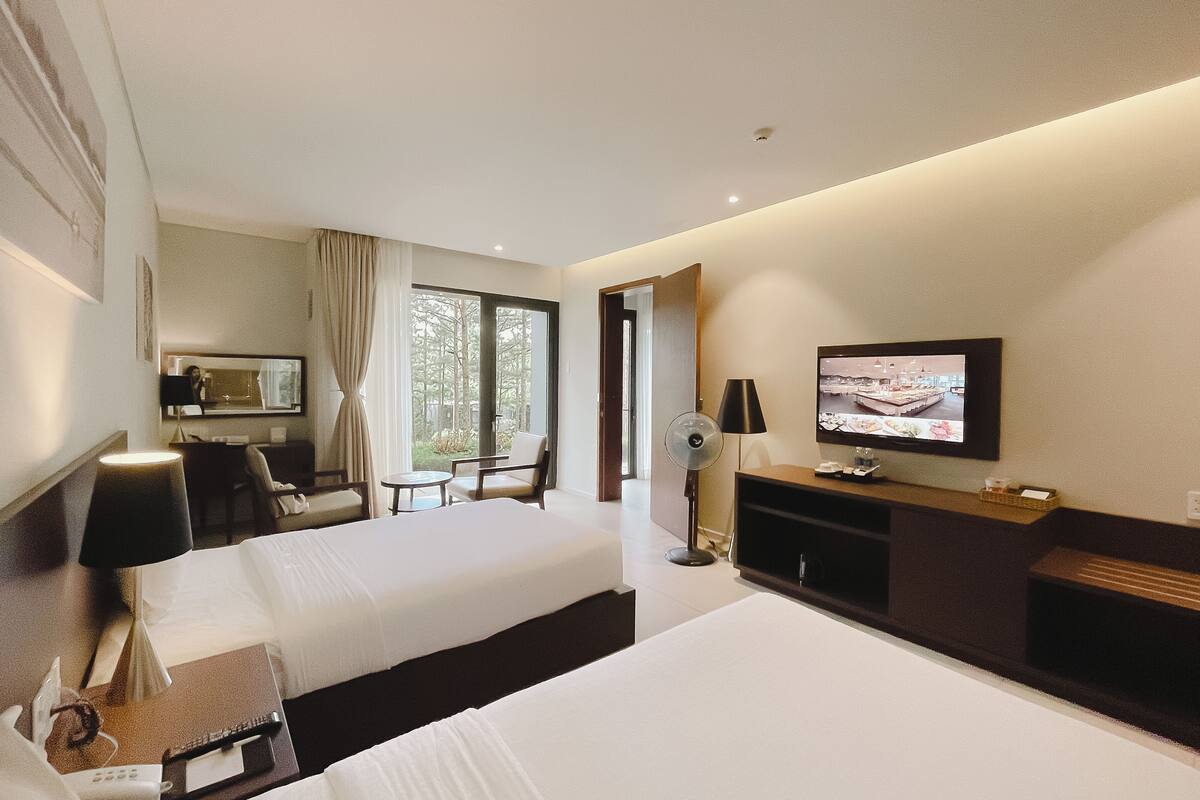 Ein Hotelzimmer mit zwei Betten, einem Fernseher, einem Schreibtisch und einem Stuhl.