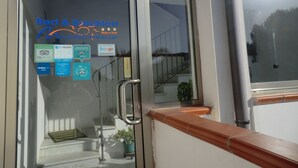 A hotel entrance with a glass door, a metal handrail, and a staircase leading inside. There are several awards and logos on the glass door, including 'ecoleader 2014' and 'Booking.com'. - B&B Mediterraneo Mare e Sole (Palma di Montechiaro)
