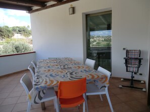 A covered patio with a table and chairs, a view of the city, and a massage chair. - B&B Mediterraneo Mare e Sole (Palma di Montechiaro)