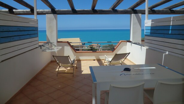 A terrace with a view of the sea, a table, and two chairs. - B&B Mediterraneo Mare e Sole (Palma di Montechiaro)