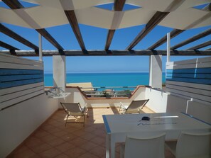 Una terraza con vista al mar, una mesa y dos sillas.